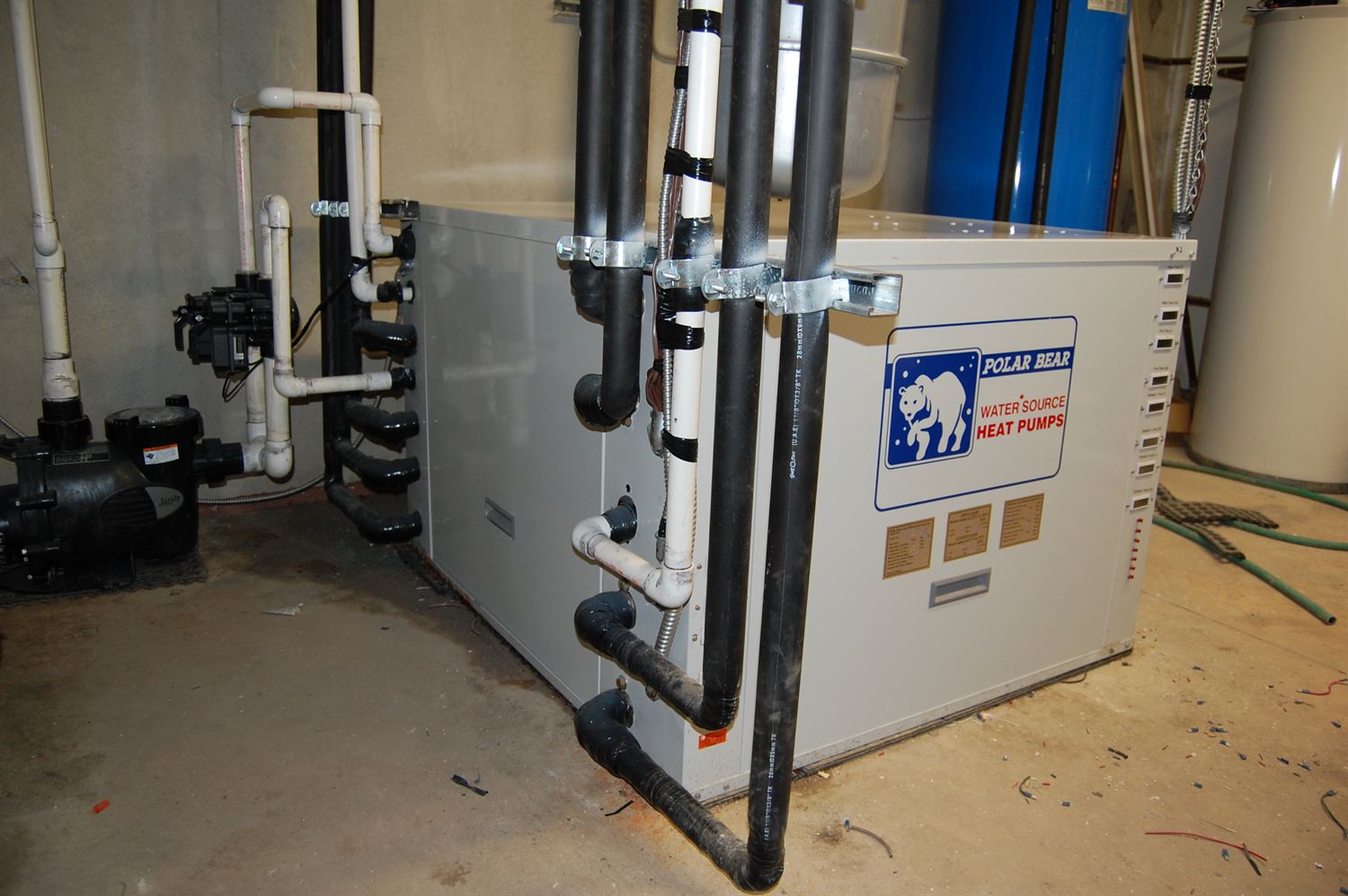 Installed heat pump with insulated supply and return piping and control wiring in a mechanical room.